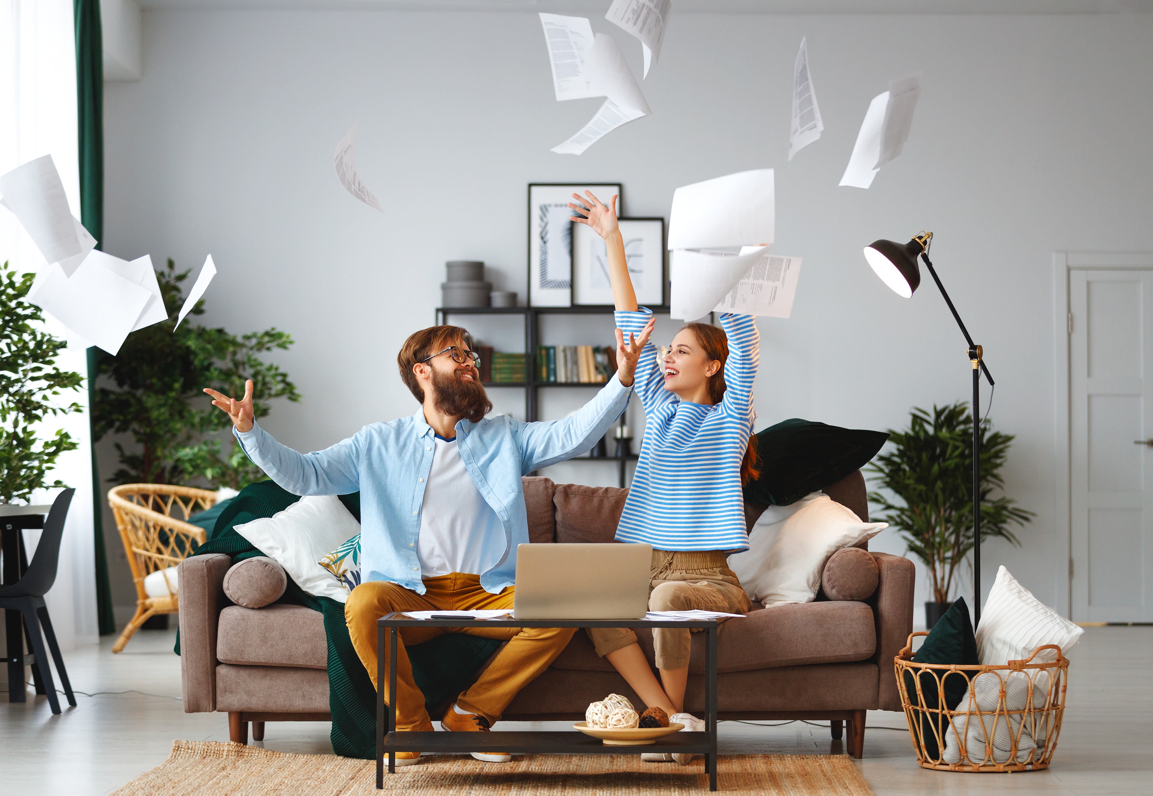 Excited couple throwing documents in the air after engaging in debt relief.